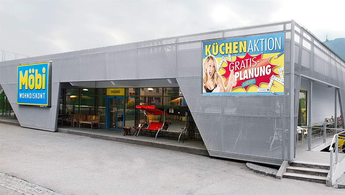Modernes Gebäude mit Möbi-Beschilderung und weiterer Werbung für eine Küchenaktion mit kostenloser Planung.
